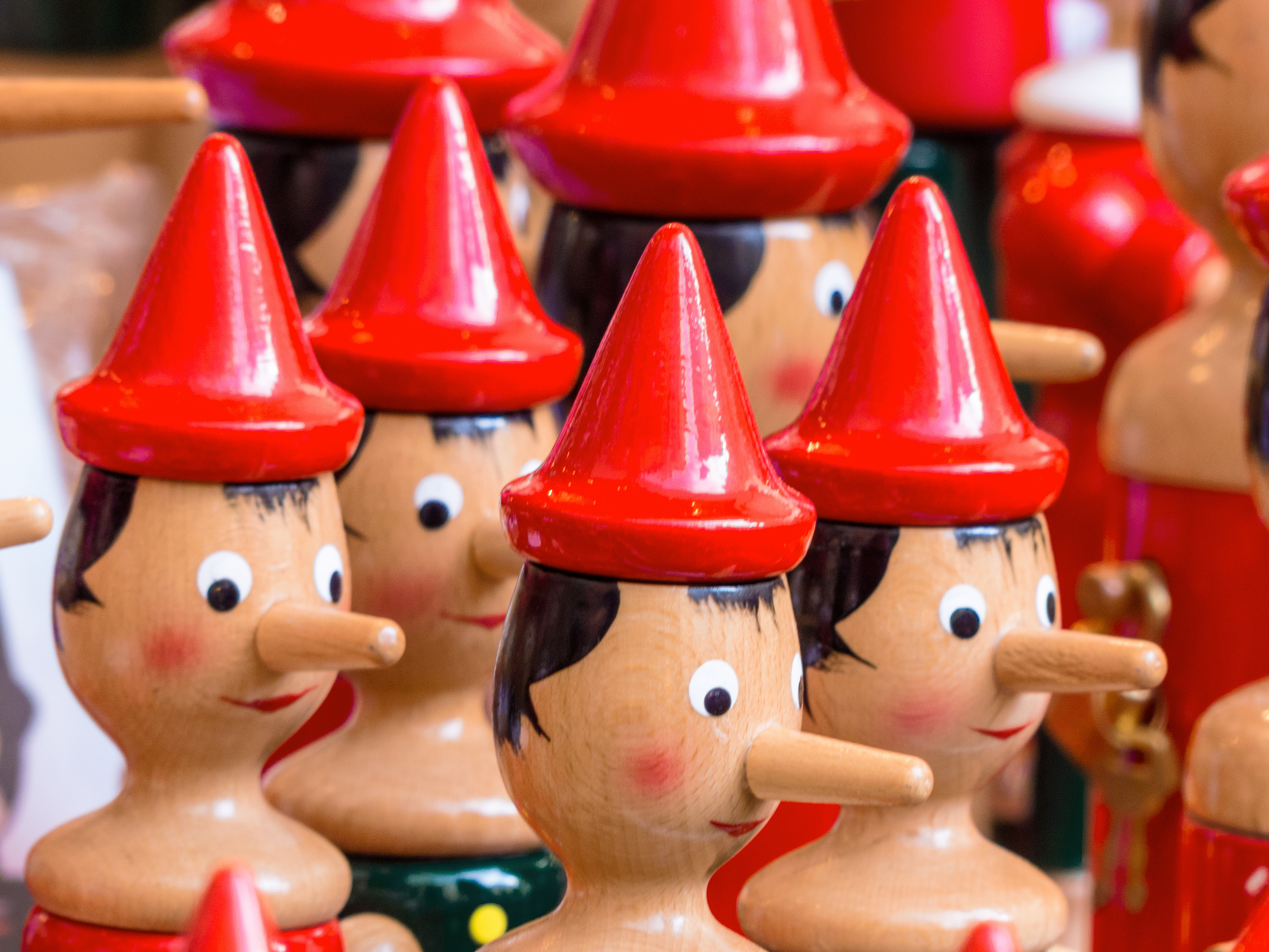 Rows of little wooden dolls with red pointed caps and extended noses.
